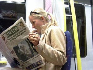 girl reading paper on subway